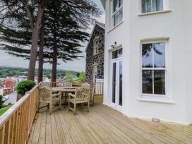 An outdoor area featuring a wooden deck with a table and chairs at Fir Grove in Menai Bridge