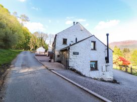 A house located on a road with trees and mountains in the background at Bramble Cottage in Thornthwaite near Braithwaite