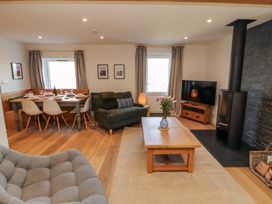 A living room with a sofa, dining table, and television at Bramble Cottage in Thornthwaite near Braithwaite