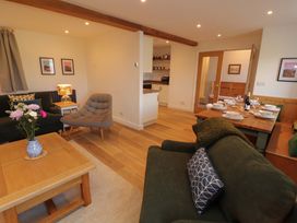 A living room with a dining area and kitchen view at Bramble Cottage in Thornthwaite near Braithwaite