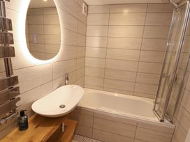 A bathroom with a bathtub, sink, and mirror at Bramble Cottage in Thornthwaite near Braithwaite