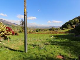 A view of grass and trees with a mountain backdrop at Bramble Cottage Thornthwaite near Braithwaite