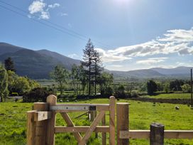 A view of mountains and fields with a fence at Bramble Cottage in Thornthwaite near Braithwaite