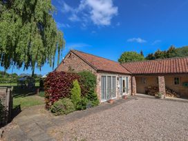 A brick house with tiled roof and large windows surrounded by plants and a gravel driveway at Providence Court Near Easingwold