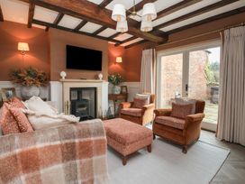 A living room with armchairs a sofa a fireplace and glass doors overlooking a patio at Providence Farmhouse near Easingwold