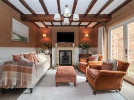A living room with sofa armchairs ottoman fireplace and television at Providence Farmhouse near Easingwold
