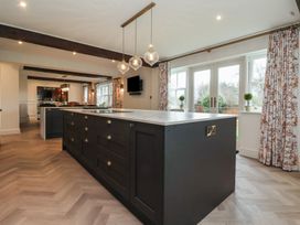 A kitchen with a large island and pendant lights overlooking a dining area with floral curtains at Providence Farmhouse near Easingwold