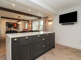 A kitchen island with dark cabinets and brass handles and a mounted TV on the wall at Providence Farmhouse near Easingwold