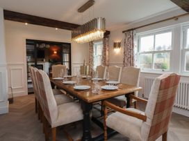 A dining room with a wooden table set for eight people and plaid upholstered chairs at Providence Farmhouse near Easingwold