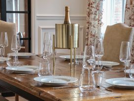 A dining table set with white plates glassware and a gold champagne bucket at Providence Farmhouse near Easingwold