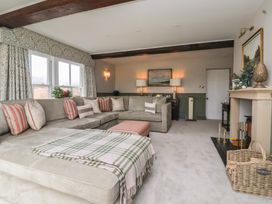 A living room with a large gray sectional sofa with cushions and a plaid blanket near windows and a fireplace at Providence Farmhouse near Easingwold