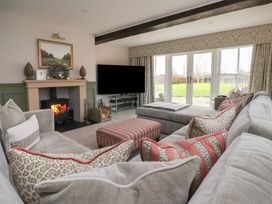 A living room with a fireplace a wall-mounted television large sofas and a view of a garden at Providence Farmhouse near Easingwold