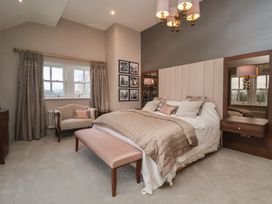 A bedroom with a large bed a bench at the foot a small sofa by window and bedside tables with mirrors at Providence Farmhouse near Easingwold