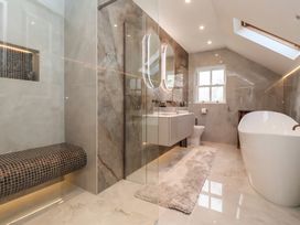 A bathroom with a freestanding bathtub a toilet a double vanity with mirrors a glass partition and a tiled bench near Providence Farmhouse near Easingwold