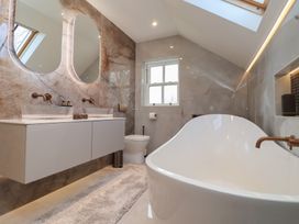 A bathroom with a freestanding bathtub sinks with mirrors a toilet and skylights at Providence Farmhouse near Easingwold
