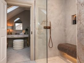 A bathroom shower area with a tiled bench and a vanity room with a stool and mirror at Providence Farmhouse near Easingwold