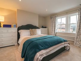 A bedroom with a bed between two white dressers and windows with floral curtains at Providence Farmhouse near Easingwold