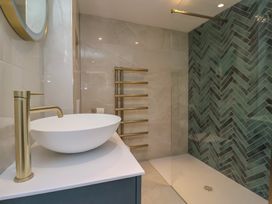 A bathroom with a white vessel sink and brass faucet next to a walk-in shower with green herringbone tiles at Providence Farmhouse near Easingwold