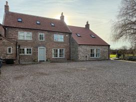 Exterior view of a two story brick house with a gravel driveway and trees near Easingwold