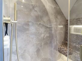 A shower area with a handheld showerhead and hose a built-in bench with mosaic tiles and a recessed shelf with lighting at Providence Farmhouse near Easingwold