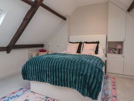 A bedroom with a bed with teal blanket and pink pillows under a slanted ceiling at Providence Farmhouse near Easingwold