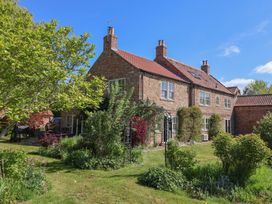 A brick house with a tiled roof and garden with trees and shrubs at Providence Farmhouse near Easingwold