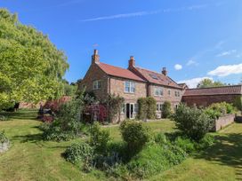 A brick farmhouse with a red tiled roof surrounded by garden and trees at Providence Farmhouse near Easingwold