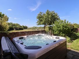 An outdoor hot tub with water jets in a garden with trees and a fence at Providence Farmhouse near Easingwold