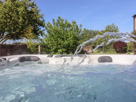 An outdoor hot tub with water jets and surrounding garden at Providence Farmhouse near Easingwold