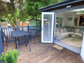 An outdoor deck with a table and chairs overlooking a living area at Evermore Lodge 48 Calgarth Park, White Cross Bay, Windermere