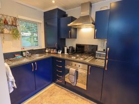 A kitchen with cabinets, countertop, sink, and cooking appliances at Evermore Lodge, 48 Calgarth Park, White Cross Bay, Windermere