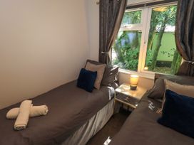 A bedroom with two single beds and a lamp at Evermore Lodge, 48 Calgarth Park, White Cross Bay, Windermere