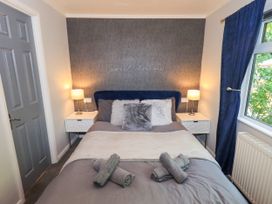 A bedroom with a bed, bedside table, and curtains at Evermore Lodge, 48 Calgarth Park, White Cross Bay, Windermere