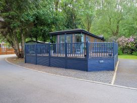 A cabin with a decking area surrounded by trees at Evermore Lodge, 48 Calgarth Park, White Cross Bay, Windermere