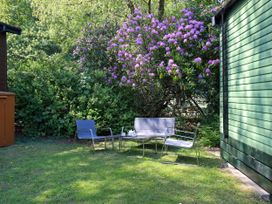 A garden with chairs and a table near a flowering bush at Evermore Lodge, 48 Calgarth Park, White Cross Bay, Windermere
