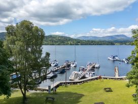 A view of boats docked at a lake with trees and grass at Evermore Lodge, 48 Calgarth Park, White Cross Bay, Windermere