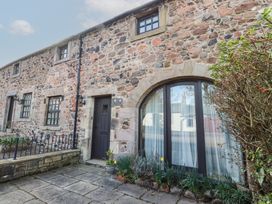 Stone exterior of a building with a door and arched window surrounded by plants at Primula Patch in Akeld near Wooler