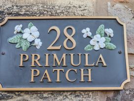 A house number plaque with the number 28 and the words Primula Patch with flower decorations at Primula Patch in Akeld near Wooler
