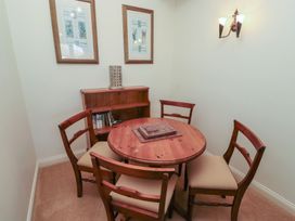 A small dining area with a round wooden table and four chairs a wooden shelving unit with books two framed pictures on the wall and a wall light at Primula Patch Akeld near Wooler