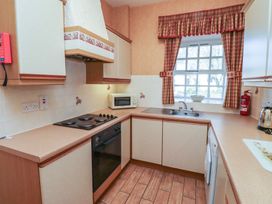 A kitchen with oven stovetop microwave sink window with checkered curtains and fire extinguisher at Primula Patch in Akeld near Wooler