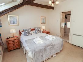 A bedroom with a double bed two bedside tables lamps and an open door leading to a bathroom at Primula Patch in Akeld near Wooler