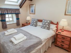 A bedroom with a double bed two bedside tables with lamps and folded towels on the bed at Primula Patch in Akeld near Wooler