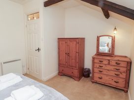 A bedroom with a wooden wardrobe a wooden dresser with mirror and a bed with towels at Primula Patch in Akeld near Wooler