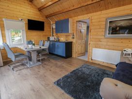 A small kitchen and dining area with a table, chairs, and blue cabinets in a wooden room at Drumrane Lodge in Dungiven Londonderry