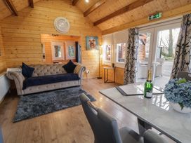 A wooden living room with a sofa a rug a table with chairs and a bottle at Drumrane Lodge in Dungiven Londonderry