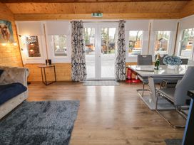A dining area with a table and chairs next to glass doors and windows showing an outdoor view at Drumrane Lodge in Dungiven Londonderry