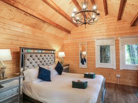 A bedroom with a large bed two bedside tables with lamps a chandelier and two windows at Drumrane Lodge in Dungiven Londonderry