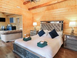 A bedroom with a bed and bedside tables with lamps next to a living area and kitchenette at Drumrane Lodge in Dungiven Londonderry
