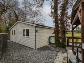 A small building with two windows and a hose on the side next to trees and a wooden structure at Railway Lodge in Dungiven Londonderry