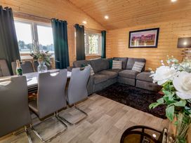 A wooden living room with a grey corner sofa white dining table and grey chairs at Railway Lodge in Dungiven Londonderry